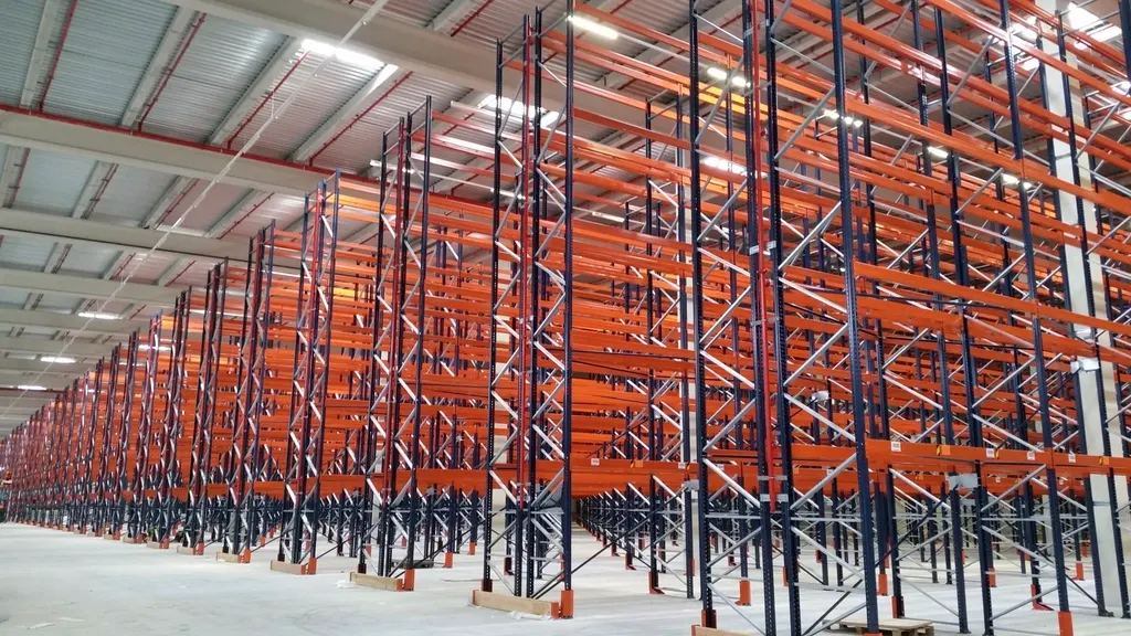 Almacén con largas filas de estanterías metálicas y palés