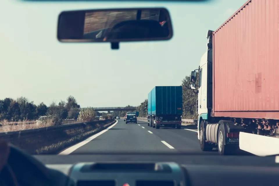 Vista desde el parabrisas de un vehículo en una autovía, con varios camiones por delante