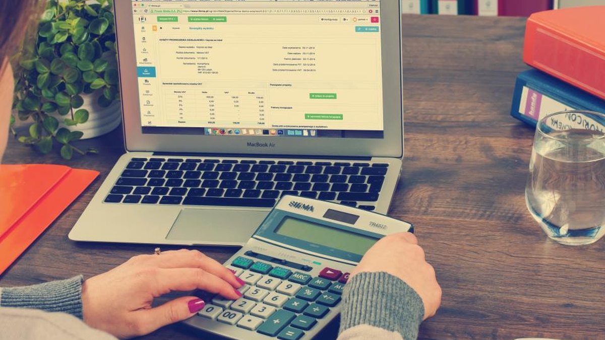 Persona trabajando con facturas y libros contables en un escritorio de oficina
